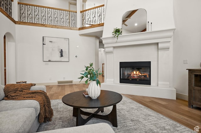 1161 Woodcrest Ln, North Salt Lake, UT 84054 - living area featuring wood finished floors, a glass covered fireplace, arched walkways, a high ceiling, and baseboards