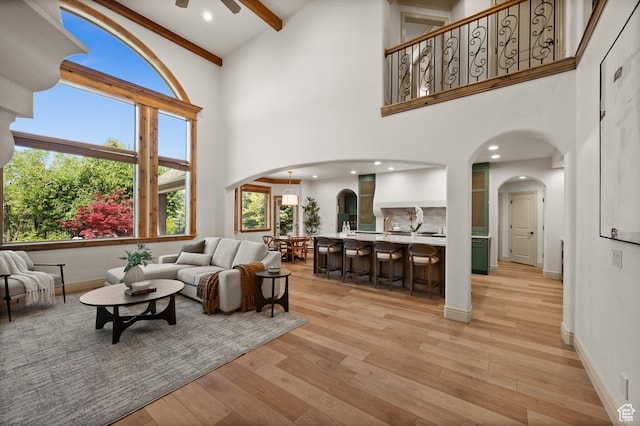 1161 Woodcrest Ln, North Salt Lake, UT 84054 - living room with arched walkways, a high ceiling, ceiling fan, light wood finished floors, and beam ceiling