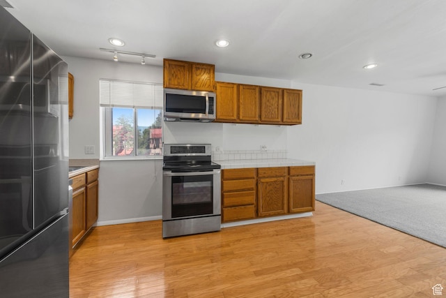 4878 S Highland Cir Unit 6, Salt Lake City, UT 84117 - kitchen with appliances with stainless steel finishes, brown cabinets, tile countertops, light wood-style floors, and recessed lighting