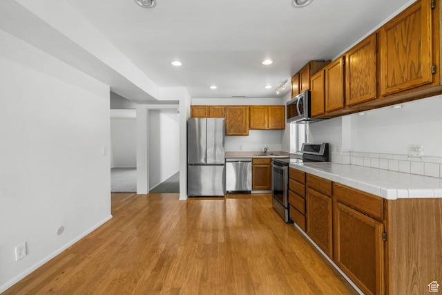 4878 S Highland Cir Unit 6, Salt Lake City, UT 84117 - kitchen featuring appliances with stainless steel finishes, brown cabinets, light wood-type flooring, baseboards, and recessed lighting
