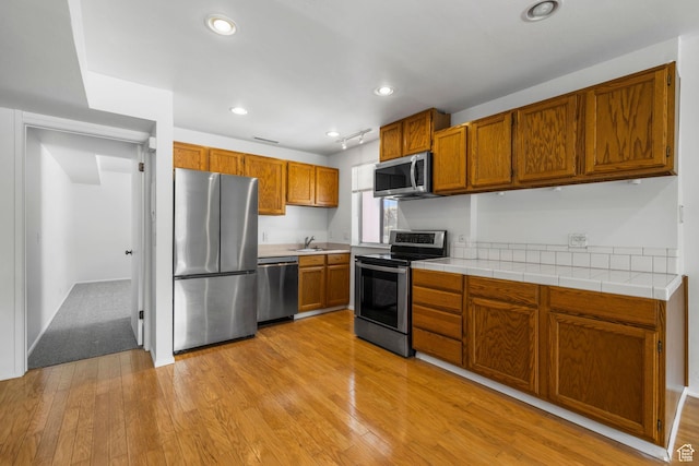 4878 S Highland Cir Unit 6, Salt Lake City, UT 84117 - kitchen featuring stainless steel appliances, brown cabinetry, a sink, light wood finished floors, and recessed lighting