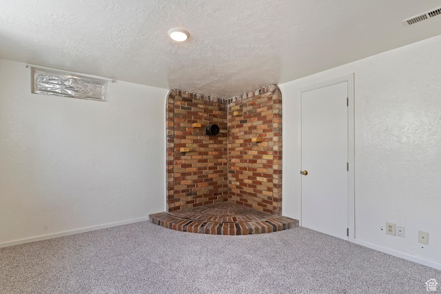 unfurnished living room with a textured ceiling, carpet floors, and baseboards