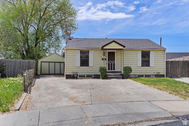 bungalow-style home with a detached garage, fence, an outbuilding, a chimney, and roof with shingles