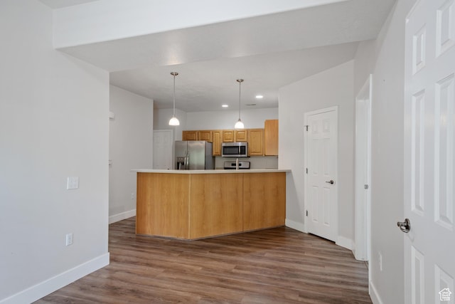 kitchen with appliances with stainless steel finishes, a peninsula, baseboards, dark wood-type flooring, and recessed lighting