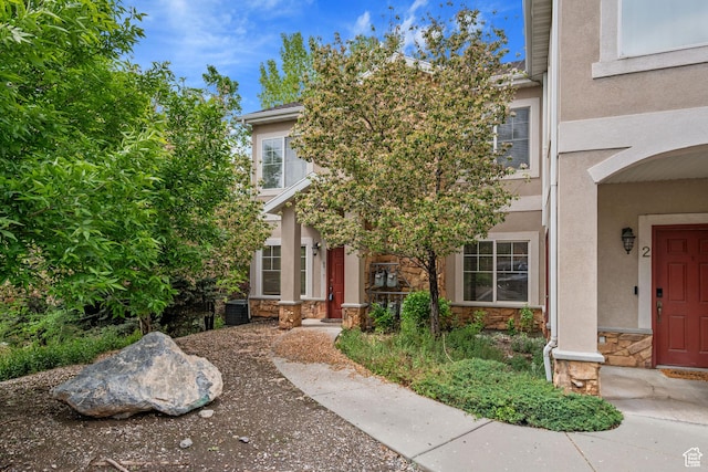 view of front of house with stone siding, stucco siding, and central AC
