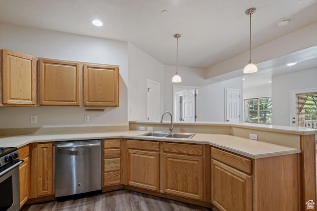kitchen with stainless steel appliances, a sink, dark wood-style flooring, a peninsula, and light countertops