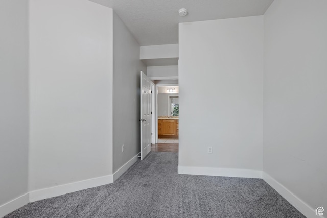 carpeted spare room with baseboards and a smoke detector