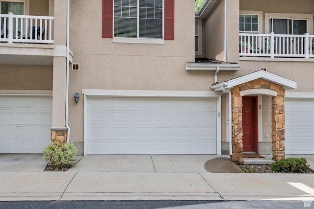 view of front of home with an attached garage, stone siding, stucco siding, and concrete driveway