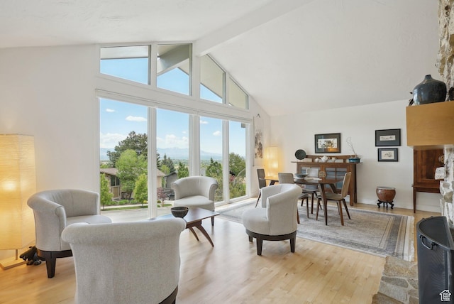 living room with high vaulted ceiling, light wood-style flooring, and beamed ceiling