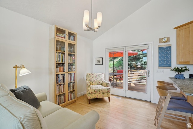 living area with a chandelier, light wood-style floors, and high vaulted ceiling