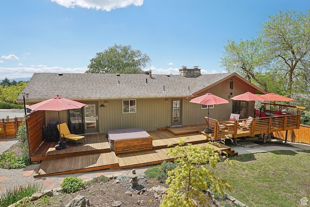 rear view of house with a shingled roof, a wooden deck, and fence