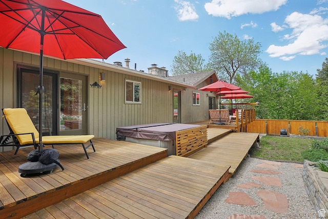 wooden terrace with a covered hot tub and fence