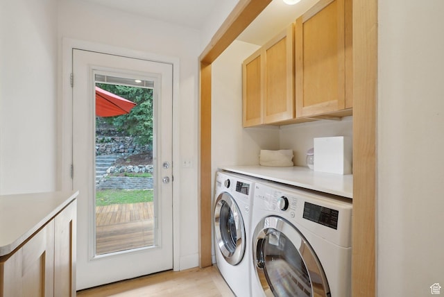 laundry area with cabinet space, separate washer and dryer, and light wood-style floors