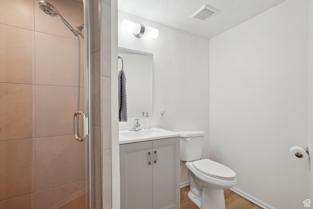 full bathroom with a stall shower, toilet, vanity, and wood finished floors