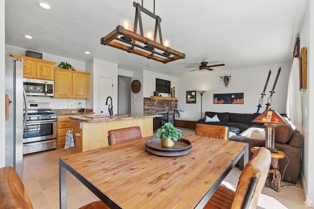 dining room with a ceiling fan, recessed lighting, and a stone fireplace