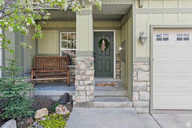 entrance to property featuring stone siding, covered porch, and a garage