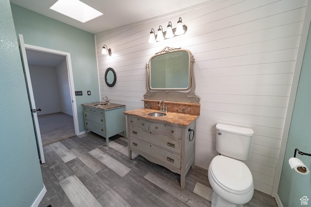 1691 E 8900 S, Price, UT 84501 - bathroom with wood finished floors, a skylight, two vanities, toilet, and wood walls