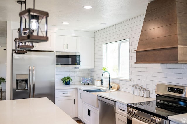 kitchen with appliances with stainless steel finishes, a sink, white cabinets, decorative backsplash, and light countertops