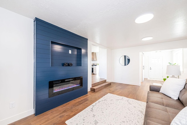 living room with a large fireplace, baseboards, and wood finished floors