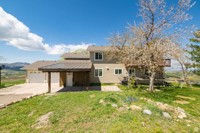 view of front of home featuring a garage, driveway, a front lawn, and a mountain view