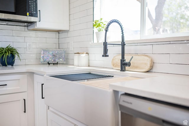 kitchen view of stainless steel microwave, dishwashing machine, and white cabinets