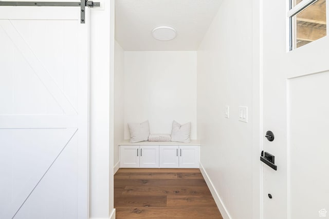 mudroom with dark wood-style floors, baseboards, and a barn door