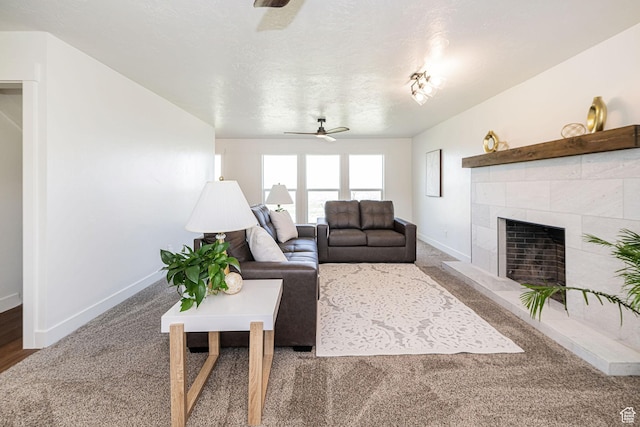 living area featuring a ceiling fan, carpet floors, baseboards, and a tile fireplace