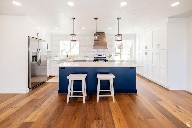 kitchen featuring stainless steel appliances, custom exhaust hood, backsplash, light countertops, and recessed lighting