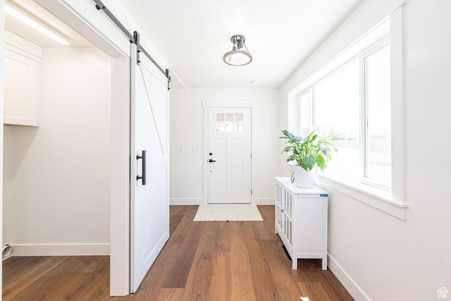 entryway featuring a barn door, wood finished floors, and baseboards