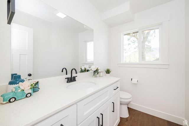 bathroom featuring toilet, baseboards, vanity, and wood finished floors