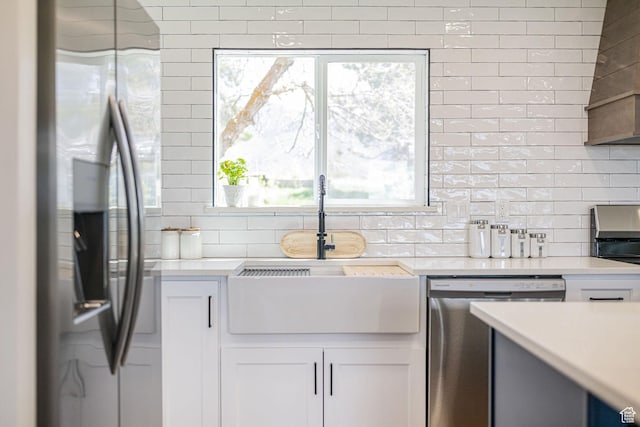 kitchen with appliances with stainless steel finishes, tasteful backsplash, light countertops, and white cabinets