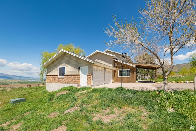 view of front facade featuring brick siding, a garage, a mountain view, a patio area, and a front yard
