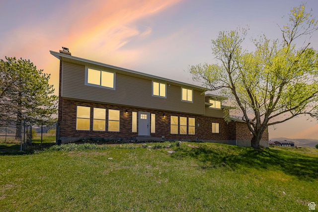 back of property at dusk featuring a chimney and brick siding