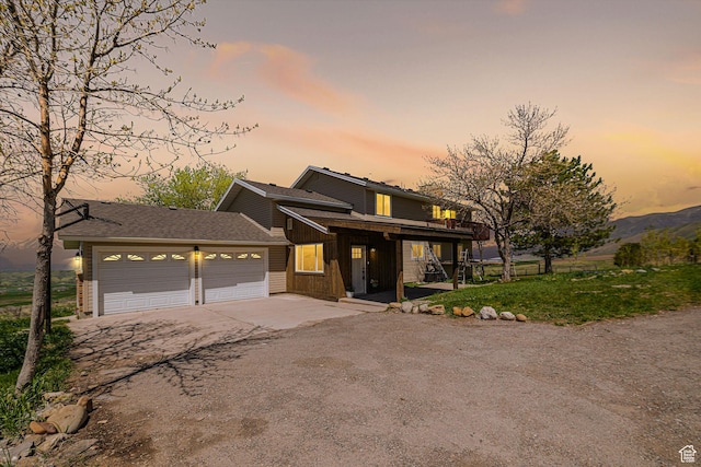 view of front of property with driveway, a garage, covered porch, and a shingled roof