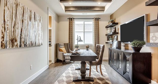 living area with a tray ceiling, wood finished floors, and baseboards