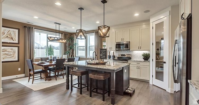 kitchen with stainless steel appliances, baseboards, white cabinets, decorative backsplash, and light stone countertops