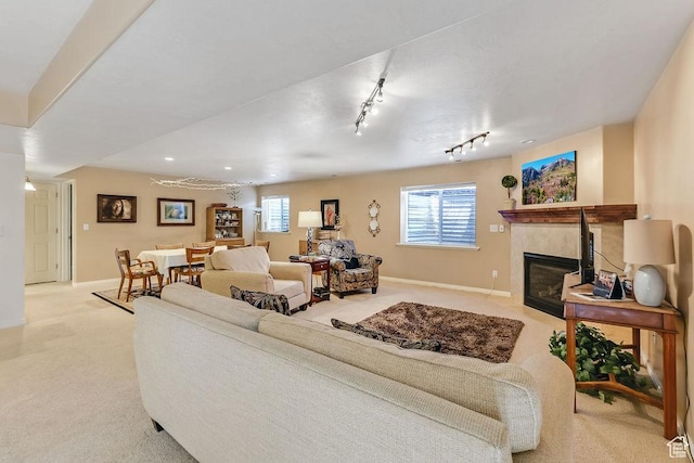 carpeted living room featuring a fireplace, baseboards, plenty of natural light, and rail lighting