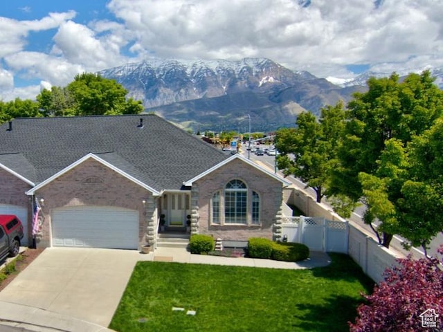 view of front facade with a mountain view, an attached garage, driveway, and brick siding