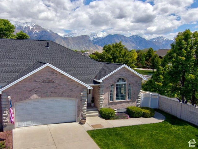 view of front of property featuring a mountain view, brick siding, concrete driveway, a garage, and a shingled roof