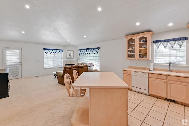 kitchen with dishwasher, light brown cabinetry, light countertops, a sink, and a kitchen island