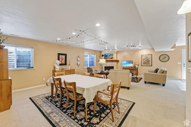 dining space featuring light colored carpet, track lighting, a fireplace, recessed lighting, and baseboards