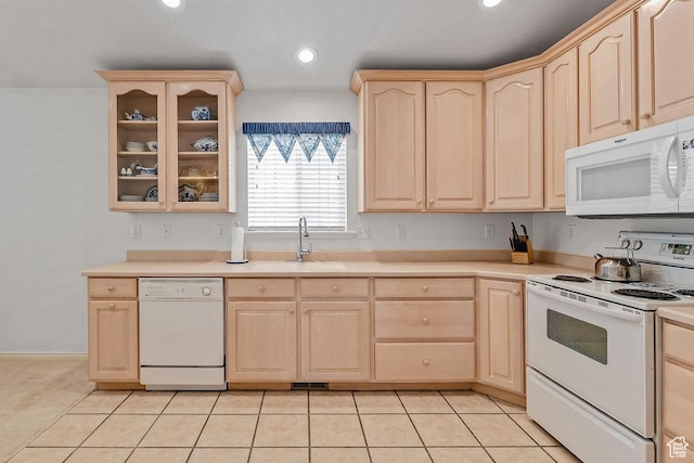 kitchen featuring white appliances, light brown cabinetry, a sink, glass insert cabinets, and light countertops