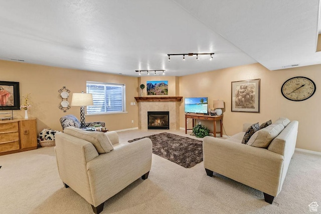 living area with light carpet, rail lighting, a tiled fireplace, and baseboards