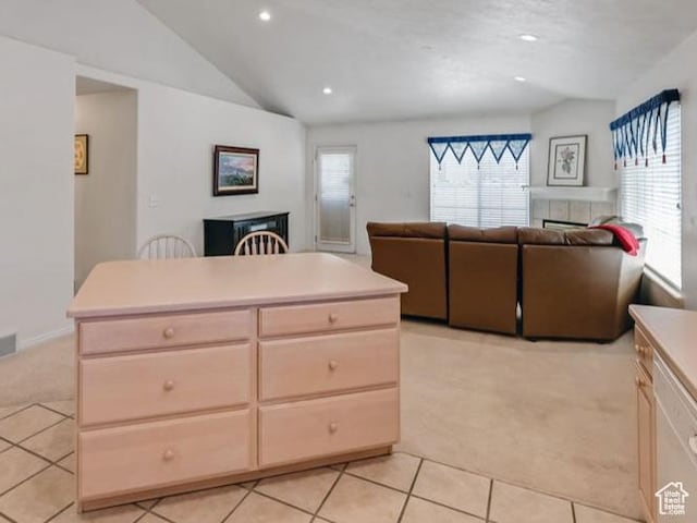 kitchen with a tiled fireplace, lofted ceiling, light carpet, light tile patterned floors, and open floor plan