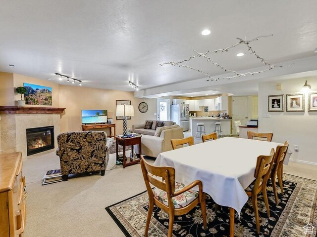 dining space with rail lighting, a tile fireplace, light colored carpet, and recessed lighting