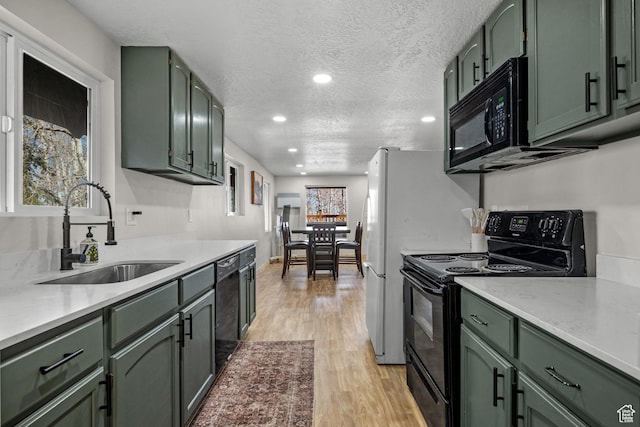 kitchen with green cabinetry, black appliances, a sink, light wood finished floors, and recessed lighting