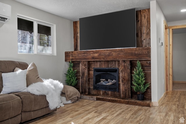living room featuring a wall mounted air conditioner, wood finished floors, a fireplace with raised hearth, and baseboards