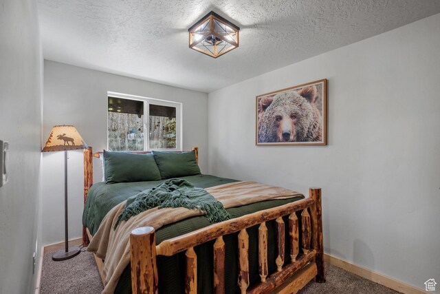 carpeted bedroom featuring a textured ceiling and baseboards