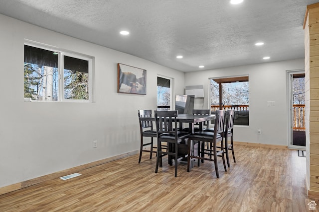 dining area with recessed lighting, a textured ceiling, light wood-style floors, and baseboards