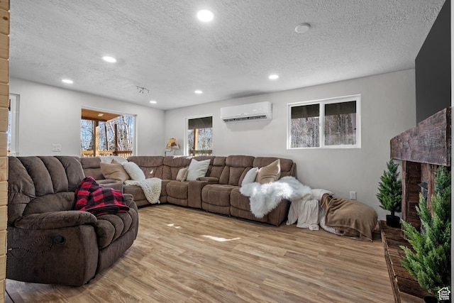 living area with light wood finished floors, an AC wall unit, a textured ceiling, and recessed lighting
